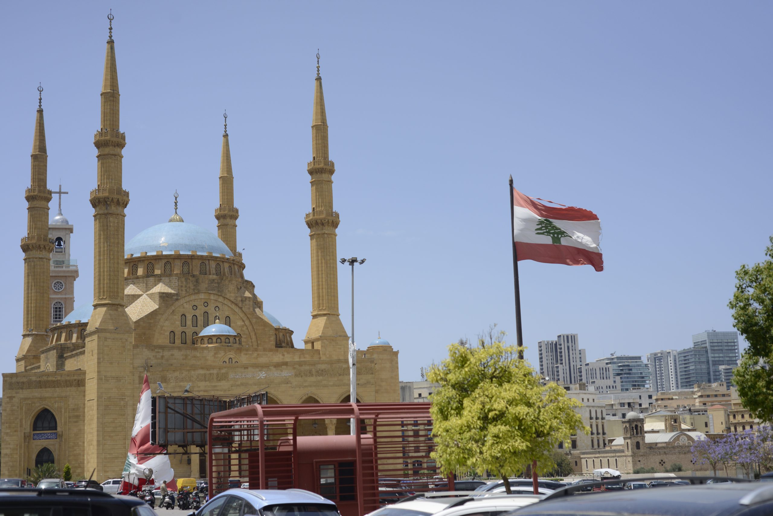 A city landscape view which shows a mosque with a Lebanese flag in the foreground