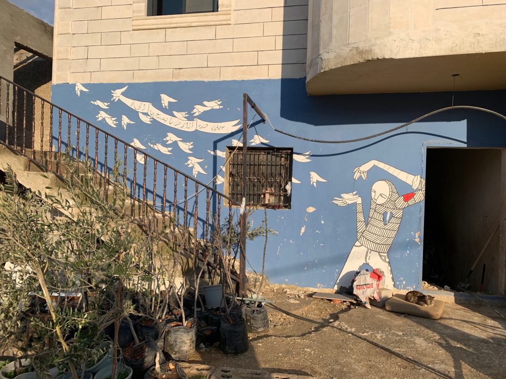 A painting on a wall showing white birds flying with a banner